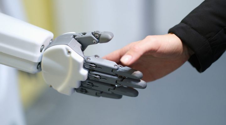 Roboter und Mensch reichen sich die Hände